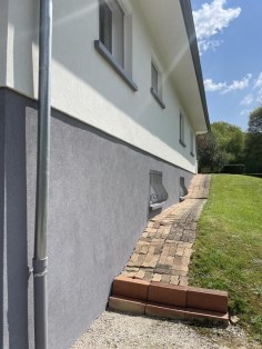 Façade de maison rénovée, enduit clair et soubassement gris